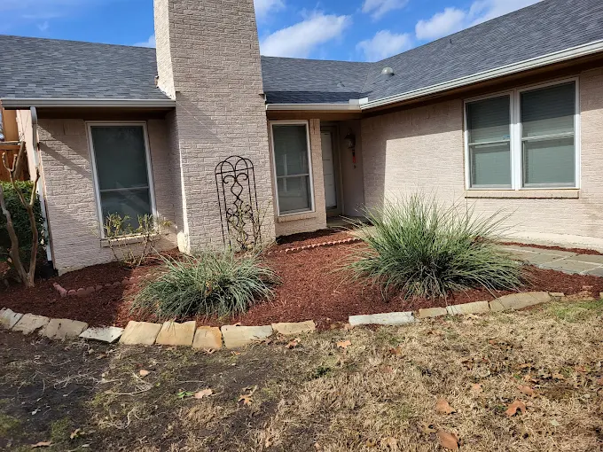 Front yard flower bed with fresh red mulch and stone edging